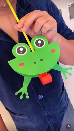 a person holding a paper cutout with a frog on it's back and eyes