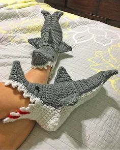 two crocheted shark gloves laying on top of a person's leg in bed