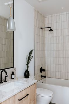 a white toilet sitting next to a bath tub under a bathroom mirror above a sink