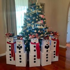 a christmas tree decorated with snowmen in front of four boxes under it, all wrapped in red and white ribbon