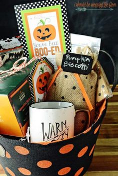 a halloween gift basket filled with books, cards and coffee mugs on a wooden table