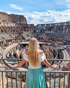 a woman standing on top of a balcony next to an old roman collise