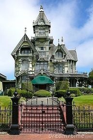 a large house with a green umbrella in front of it and some bushes on the other side