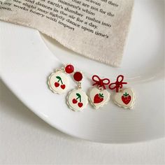 three cherries on a white plate next to a napkin and some type of book