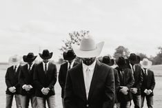 a group of men in suits and hats standing next to each other on a field