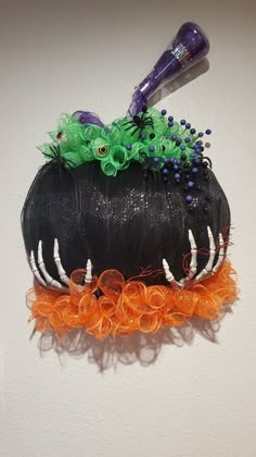 a hair dryer sitting on top of a black hat with orange and green decorations