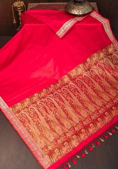 Indulge in luxury and sophistication with our Red Tanchoi Jamawar Banarasi Saree in Pure Silk. Adorned with intricately woven Jamawar Paisley motifs using the Tanchoi weave on just the pallu, this exclusive designer piece features a subtle zari border that adds a touch of elegance. Crafted from the finest Pure silk fabric, this saree exudes timeless beauty and artistry. SILK MARK CERTIFIED This saree is ready to wear with fall and pico done. Handmade silk tassels adorn the pallu and add more grace to it. An unstitched blouse fabric is included. *Note: There may be minor variations in the shade, the texture of the product. Hues/textures show differently due to variations in screen settings and other factors, *Note: This is a handwoven saree and there may be slight inconsistencies such as in Paisley Motifs, Silk Tassels, Banarasi Saree, Christmas Deals, Banarasi Sarees, Blouse Fabric, Pure Silk, Silk Fabric, Saree Designs