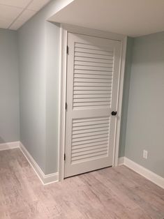 an empty room with two doors and hard wood flooring on the side of the room