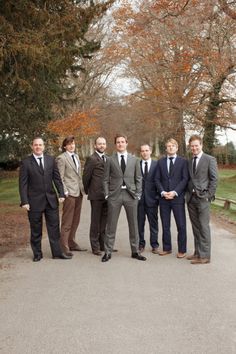 a group of men standing next to each other on a road in front of trees