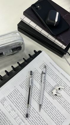 an open notebook with two pens on top of it next to a computer mouse and keyboard