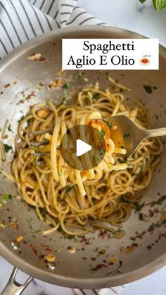 spaghetti in a skillet being stirred with pesto and olive oil by a fork