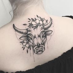 a woman's upper back tattoo with an oxen and flowers on her neck