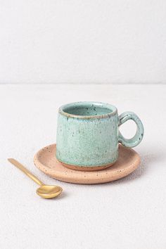 a small cup and saucer sitting on a plate with a spoon next to it