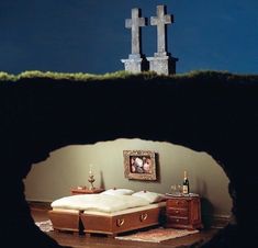 two crosses on top of a hill with a bed in the foreground and a dresser below