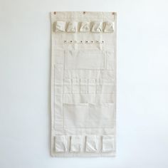 a white wall hanging on the side of a wall with several pieces of paper attached to it