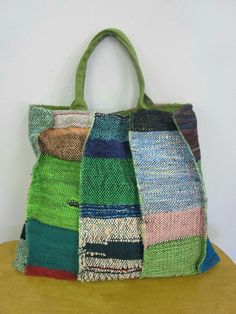 a multicolored handbag sitting on top of a wooden table next to a white wall