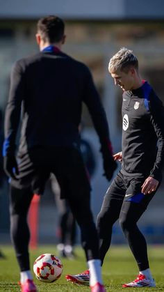 two soccer players are on the field playing with a ball and one is wearing red shoes