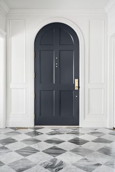 a black and white checkered floor in front of a blue door with gold hardware