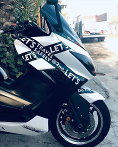 a white and black motorcycle parked next to a tree