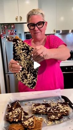 a woman is holding up some food in her hands while standing at the kitchen counter