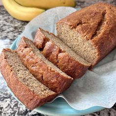 sliced loaf of banana bread on a blue plate with two bananas in the back ground