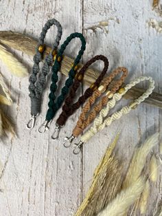 four different colors of hair ties on a white wooden surface with feathers in the background