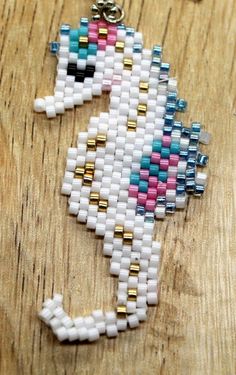 a white and blue beaded unicorn keychain sitting on top of a wooden table