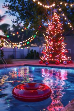 a christmas tree is lit up in the background with lights around it and an inflatable tube floating on top