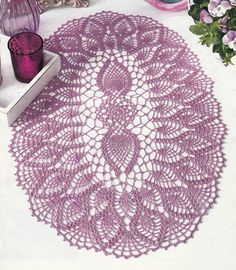 a crocheted doily is sitting on a table next to some vases