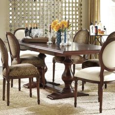 a dinning room table with chairs and a vase on the table in front of it