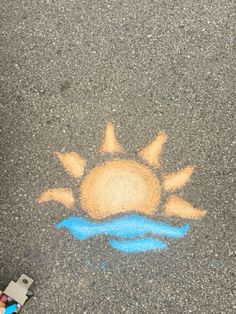 the sun is drawn on the asphalt with chalk and crayon pencils next to it