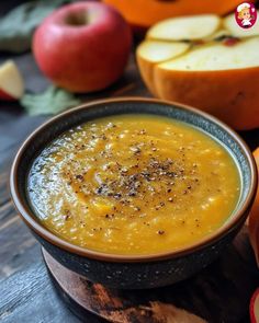 a bowl filled with soup next to sliced apples