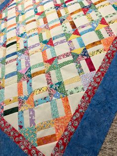 a colorful quilt on the ground with blue border