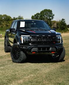 a black truck parked on top of a grass covered field