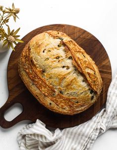 a loaf of bread sitting on top of a wooden cutting board next to a flower