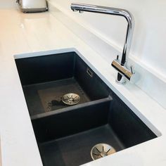 a kitchen sink under a faucet in a white counter top