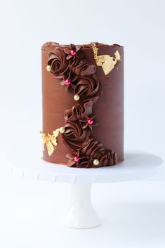 a chocolate cake with flowers and gold decorations