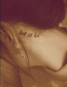 a woman with a tattoo saying let it be on her back behind her ear and the word let it be written in cursive