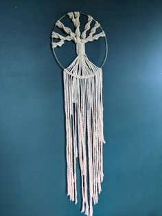 a macrame hanging on the wall in front of a blue wall with a tree