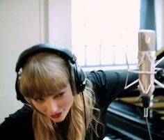 a woman wearing headphones in front of a microphone and recording equipment on a desk