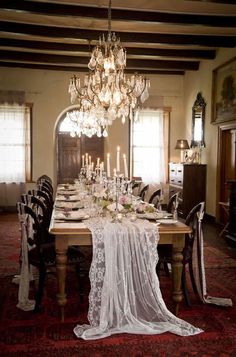 the dining room table is set with an elegant chandelier and white linens