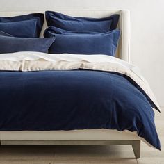 a bed with blue and white linens in a minimalistic bedroom setting on a wooden floor