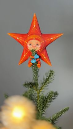 an orange star ornament hanging from a christmas tree