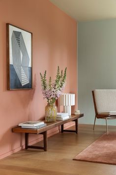 a living room with pink walls and wooden furniture in the corner, along with a painting on the wall