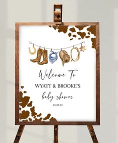 a welcome sign is hanging on a wooden easel with clothes and shoes in the background