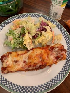 a white plate topped with meat covered in cheese and salad next to a bottle of water