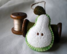 a green and white stuffed animal next to a spool of thread on a bed