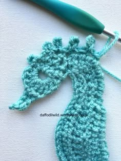 the crocheted giraffe is being worked on with a green knitting needle