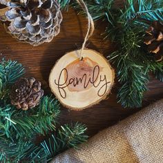 a wooden ornament with the word family hanging from it's center surrounded by pine cones