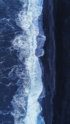 an aerial view of the ocean with waves coming in from the water and ice on the shore